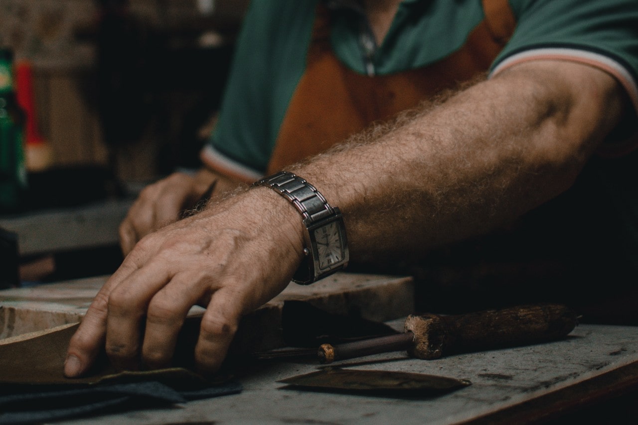 a man working with his hands and wearing a Cartier Tank watch