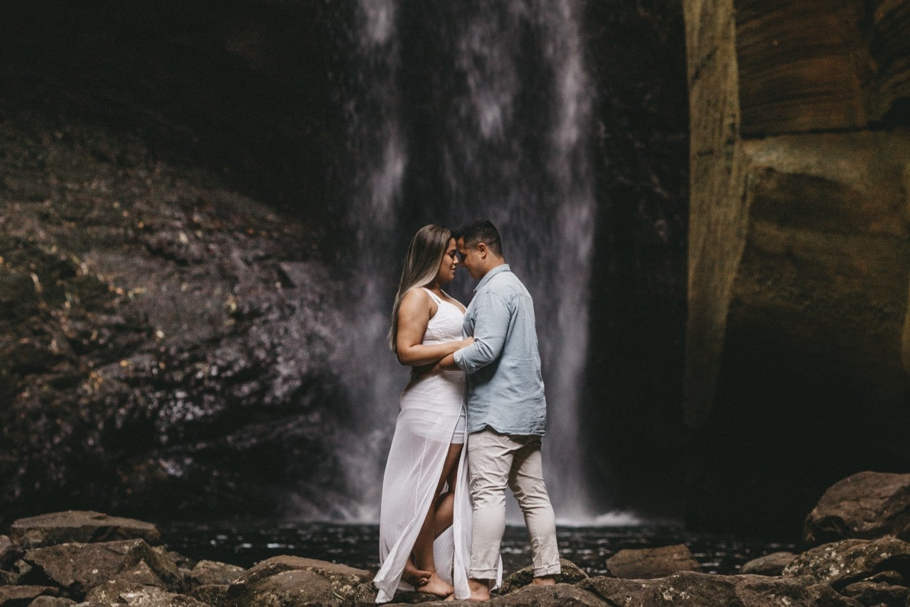 a couple standing near a waterfall and embracing