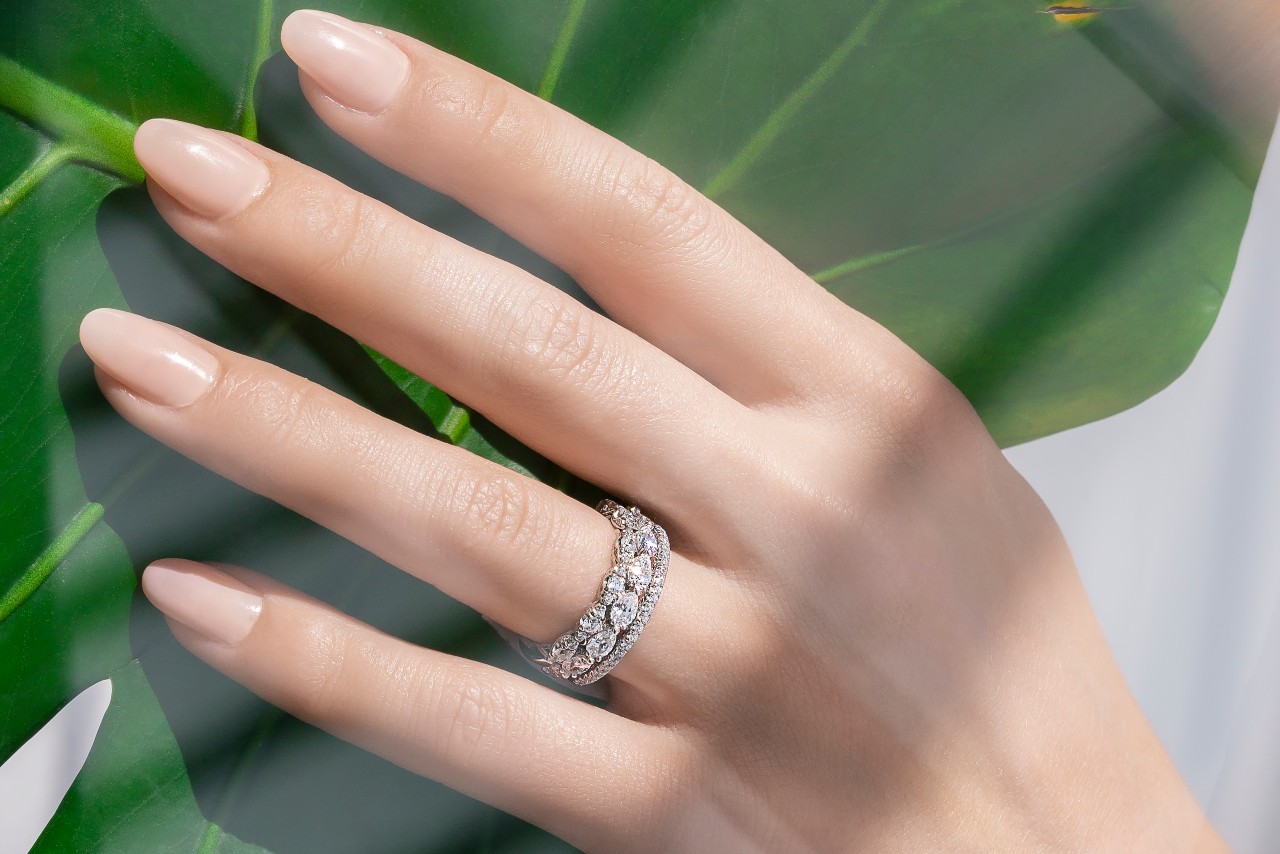a lady&rsquo;s hand wearing wedding bands by TACORI