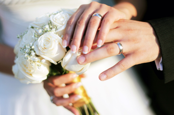 Bride and Groom holding hands with wedding bands